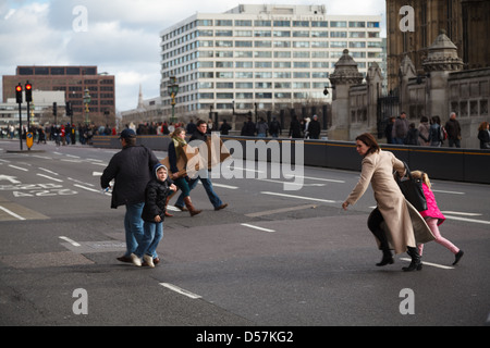 Eine Familie zögern während versuchen, überqueren eine Straße und laufen zurück zur Vermeidung von schnellen Verkehr auf Westminster Bridge Stockfoto