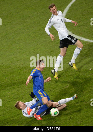 Deutschlands Marco Reus (unten) wetteifert um den Ball mit Kasachstans Genrikh Shmidtgal, beobachtet von Deutschlands Per Mertesacker (R) während der FIFA WM 2014 Qualifikation Gruppe C Fußballspiel zwischen Deutschland und Kasachstan in Nürnberg Arena in Nürnberg, 26. März 2013. Foto: David sollte/dpa Stockfoto