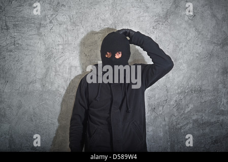 Verwirrt Einbrecher Konzept, Dieb mit Sturmhaube erwischt und vor die Betonwand Grunge verhaftet. Stockfoto