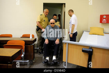 Beschuldigt Nazi Death camp Wache, die John Demyanyuk (C) in einem Rollstuhl sitzt, als er in einem Gerichtssaal in München, Deutschland, 15. Juni 2010 kommt. 89-Year-Old Demyanyuk, beschuldigt, ein Wachmann an einem NS-Vernichtungslager Sobibor, hat die Aufgabe bei der Ermordung von 27.900 Juden und andere in Sobibor, gehört ein Netzwerk von Lagern, die durch das NS-Regime in Osteuropa während des zweiten Weltkriegs errichtet Stockfoto