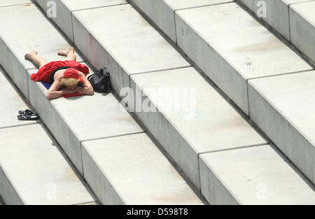 (Dpa-Datei) Ein Datei-Bild datiert 10. Juni 2010 einer Frau, die auf Treppen in Magdeburg, Deutschland Sonnenbaden ist. Am wärmsten Tag des Jahres so weit wurden in der Stadt in der Nähe Fluss Elbe Temperaturen bis zu 27 Grad Celsius gemessen. Laut Meteorologen steigen die Temperaturen in den kommenden Tagen.  Foto: Jens Wolf Stockfoto