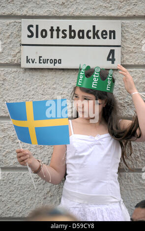 Ein kleines Mädchen, hielt die schwedische Flagge in der Hand und trägt eine Krone, Uhren Schwedens Kronprinzessin Victoria und Prinz Daniel, Herzog von Vastergotland (beide ungesehen) während der Trauerzug durch die Innenstadt von Stockholm nach ihrer Hochzeit in Stockholm, Schweden, 19. Juni 2010. Foto: Frank Mai Stockfoto