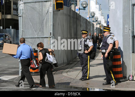 Passanten laufen vorbei an großen Absperrgitter und Polizisten in Toronto, Kanada, 24. Juni 2010. Staats-und Regierungschefs der industrialisierten Staaten sammeln im nahe gelegenen Muskoka und dann in Toronto für die G8- und G20-Gipfel vom 25-27. Juni 2010. Foto: Peer Grimm Stockfoto