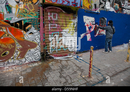 Mann malen Graffiti in Belleville, Paris, Frankreich. Es ist eine hohe Zuwanderung Gegend der Hauptstadt Stockfoto