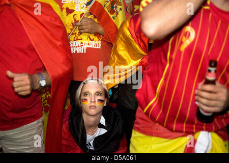 Ein deutscher Fan sitzt zwischen den spanischen Fußball-Fans in der Ahrbergsquarter in Hannover nach dem Sieg der spanischen Fußball-Nationalmannschaft über Deutschland während der FIFA WM 2010 in Südafrika, Deutschland, 7. Juli 2010 zu feiern. Foto Michael Löwa Stockfoto