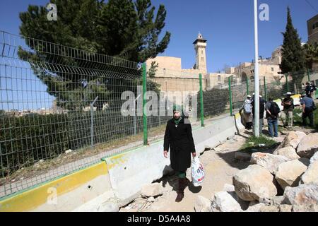 11. März 2013 - Hebron, Westjordanland, Palästinensische Autonomiegebiete - A palästinensische Frau auf einen Fußgänger Durchgang geht durch die Nachbarschaft von al-Salaimeh leitet und führt zum Grab der Patriarchen in der Mitte von Hebron im Westjordanland th, 27. März 2013. Israelische Sicherheitskräfte angelegt ein Maschendrahtzaun, die Straße längs geteilt. Auf der einen Seite des Zaunes ist eine asphaltierte Straße und auf der anderen Seite einen schmalen Fußgänger Durchgang. Da der Zaun errichtet wurde, haben israelische Sicherheitskräfte Palästinenser zu Fuß auf der Straße nicht gestattet. Stattdessen leiten sie Palästinenser an den schmalen Durchgang, welche i Stockfoto