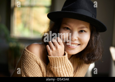 Schöne junge asiatische Modell mit schwarzem Hut und braunen Pullover zu Hause. Stockfoto