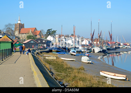 Leute, die entlang der Ufermauer spazieren, gehen am Fluss Blackwater am Hythe Quay bei Ebbe mit der St Marys Kirche hinter Maldon Essex England Stockfoto