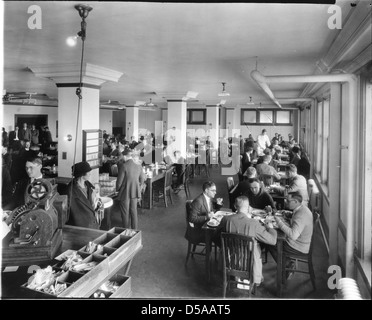 Dieses Bild zeigt den Speisesaal einer Hauswirtschaftskanteria, wahrscheinlich um 1915. Es war Teil der Bildungseinrichtungen an der Cornell University und spiegelt den Fokus der Ära auf praktische Haushaltswissenschaft und Ernährung wider. Stockfoto