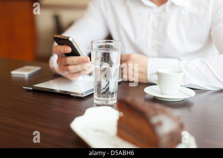 Kaffeepause mit Tablets und Smartphones, Glas Wasser im Fokus Stockfoto