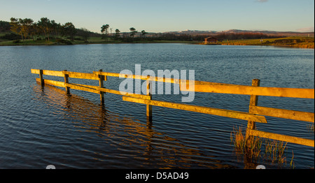 Die Knapps Loch in der Nähe von Kilmacolm Renfrewshire Schottland im Morgengrauen mit dem Sonnenlicht auf einen Zaun und Bäume. Stockfoto