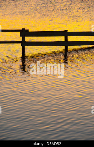 Sonnenaufgang über einen Zaun in das Wasser des Knapps Loch Kilmacolm Stockfoto