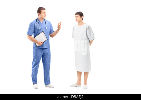 In voller Länge Portrait eines männlichen Patienten in einem Krankenhauskleid und Arzt während einer Diskussion isoliert auf weiss Stockfoto