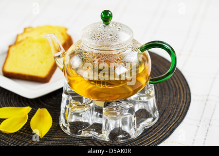 Grüner Tee im Glas Teekanne mit Pfund Zitronenkuchen im Hintergrund Stockfoto