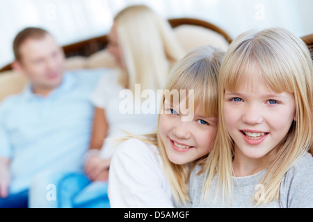 Close-up Portrait von liebevollen Zwillinge mit ihren Eltern im Hintergrund Stockfoto