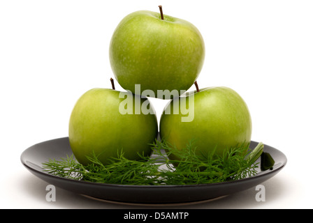 Drei Äpfel mit Dill auf einer schwarzen Platte Stockfoto