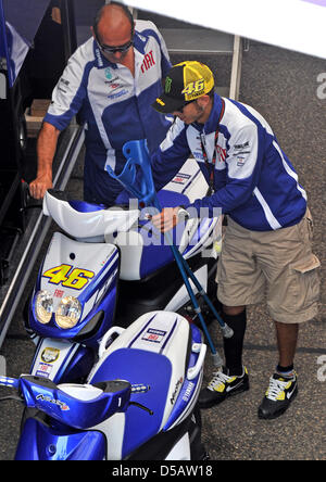 Der italienische Yamaha Fahrer und MotoGP Superstar Valentino Rossi benutzt seine Krücken, um von einem Scooter im Fahrerlager bei der Motorrad Grand Prix auf dem Sachsenring in Hohenstein-Ernstthal, Deutschland, 16. Juli 2010 steigen. Mugello wird in einem Rennen der Motorrad-Königsklasse "MotoGP" zum ersten Mal nach seinem schweren Unfall vor 40 Tagen teilnehmen. Foto: Hendrik Schmidt Stockfoto