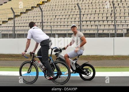 Alongh mit Renn-Ingenieur Andrew Shovlin (L), deutsche Formel1 Rennfahrer Michael Schumacher (Mercedes GP) Fahrten durch die Boxengasse auf ein Elektrofahrrad auf dem Hockenheimring in Hockenheim, Deutschland, 22. Juli 2010. Foto: Carmen Jaspersen Stockfoto