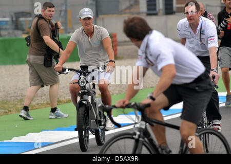 Zusammen mit Ingenieur Andrew Shovlin (R) racing, reitet deutsche Formel1 Rennfahrer Michael Schumacher (Mercedes GP) (L) durch die Boxengasse auf ein Elektrofahrrad auf dem Hockenheimring in Hockenheim, Deutschland, 22. Juli 2010. Foto: Carmen Jaspersen Stockfoto