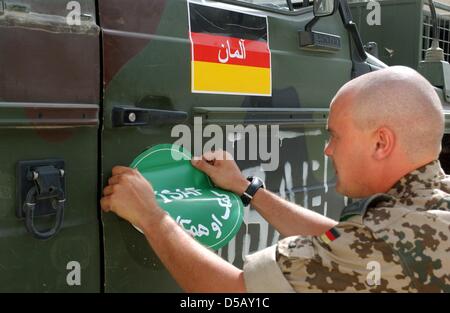 ARCHIV - Ein Bundeswehrsoldat Bringt am 5.8.2003 in Kabul eine Einems epixx, eine DM Bereits sterben Deutsche Fahne Mit Dem Arabischen Schriftzug "Deutschland" Prangt, Das Grüne Schild der Internationalen Afghanistan-Schutztruppe (ISAF) ein (Archivfoto). Kommandoaktionen, Gezielte Tötungen Und Fehlschläge - Das Nachrichtenmagazin «Der Spiegel» Sowie Die Zeitungen «New York Times» Stockfoto