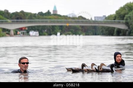 Pia Marie Witt (R) und Wilfried Arnold Schwimmen mit Enten in Kassel, Deutschland 2. August 2010. Sie werden zusammen mit den Tieren in der Nordsee schwimmen, indem Sie nach dem Fluss Fulda. Sie sind ausgestattet mit Neoprenanzügen und flossen die 485 km Distanz gehen und ihre Reise in Kassel begonnen haben, während ein Volksfest für die erste Stufe am 2. August. Sie wollen Bremerhaven erreichen Stockfoto
