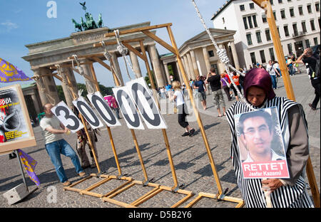 Eine Frau steht vor dem Brandenburger Tor mit einer Schlinge um den Hals zwischen Galgen und ein Bild eines Gefangenen in ihren Händen hält. Mit Protesten und Straßentheater der nationalen iranischen Widerstand fordert die Abschaffung der Todesstrafe und erinnert an ein Massaker, bei dem im Jahr 1988 30,000 politische Gefangene getötet wurden. Foto: Robert Schlesinger Stockfoto