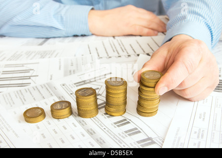 Stapel von Goldmünzen wie Spalten über verschiedene Dokumente Papierhintergrund erhöhen. Ergebnis oder rettende Diagramm (Diagramm). Stockfoto