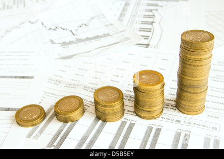 Stapel von Goldmünzen wie Spalten über verschiedene Dokumente Papierhintergrund erhöhen. Ergebnis oder rettende Diagramm (Diagramm). Stockfoto