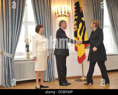 German Federal President Horst Koehler (C) und Frau Eva Luise (L) German Federal Chancellor Angela Merkel (R) an den Anfang des neuen Jahres im Schloss Bellevue in Berlin, Deutschland, 12. Januar 2010 zu begrüßen. Warten Sie im Hintergrund auf der rechten Seite Mitglieder des Kabinetts für ihren Anruf. Unter den mehr als 300 Gäste beim Neujahrsempfang des Bundespräsidenten waren Botschafter Stockfoto