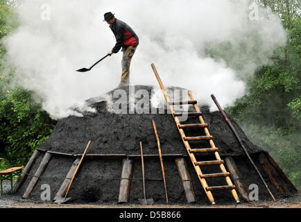 Jürgen Berger aus dem Schwarzwald verarbeitet einen rauchigen Holzkohlen Haufen in den Hotzenwald-Gemeinschaft Dachsber-Wolpadingen (Kreis Waldshut), Deutschland, 5. August 2010. Wie viele Jahre jetzt, ein Haufen Kohle für diesen Sommer im Wald zusammengestellt und feierlich angezündet. Am 10. September der Haufen geöffnet werden und die Kohle zum Verkauf angeboten. Foto: Rolf Haid Stockfoto