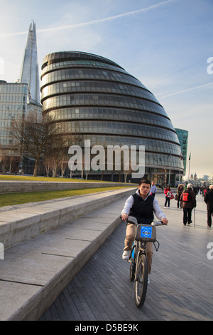 Ein Mann Radfahren "Boris" vor dem Rathaus am Südufer der Themse in London. Stockfoto