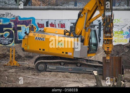 Eine Baumaschine arbeitet hinter der ehemaligen Berliner Mauer an der East Side Gallery in Berlin, Deutschland, 28. März 2013. Vier Elemente der Mauer wurden entfernt, um Platz für einen Zugang zu einer Baustelle zu machen. Ein Investor plant ein Hochhaus-Wohnung auf dem Grundstück direkt an der Spree. Foto: SOEREN STACHE Stockfoto