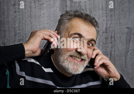 Porträt von wütenden betonte Geschäftsmann mit zwei Handys auf Grunge Hintergrund Stockfoto