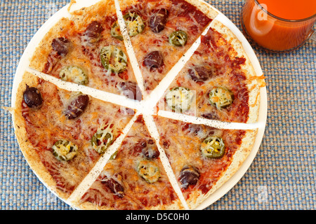 Gesunden Tortilla Wrap Pizza. Tortilla Kruste dünne Pizza mit Tomatenmark, Mozzarella-Käse, Jalapeños, Kalamata-Oliven, Pfeffer in der Nähe von klarem Glas-Tasse Stockfoto