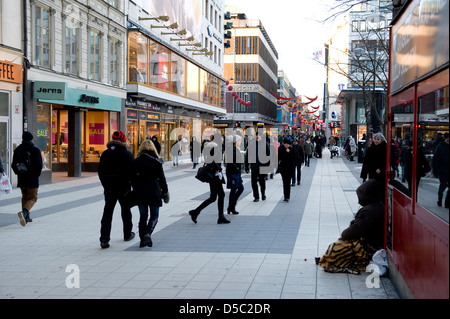 Ein Bettler sitzt in den kalten Wintermonaten auf eines der wichtigsten Einkaufsstraßen in Stockholm, Schweden. Stockfoto