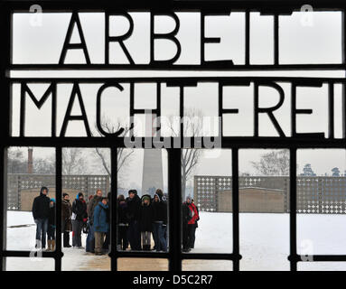 Besucher stehen auf dem Exerzierplatz des ehemaligen Konzentrationslagers Sachsenhausen hinter den Schriftzug "Arbeit Macht Frei" ("Arbeit bringt Freiheit") in Oranienburg, Deutschland, 27. Januar 2010. Die Trauerfeier findet am Holocaust-Gedenktag. Foto: BERND SETTNIK Stockfoto