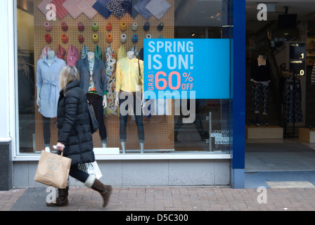 Frau geht vorbei an einem Bekleidungsgeschäft mit 60 % Rabatt beim Quelle Ausverkauf, Kingston nach Themse, Surrey, england Stockfoto