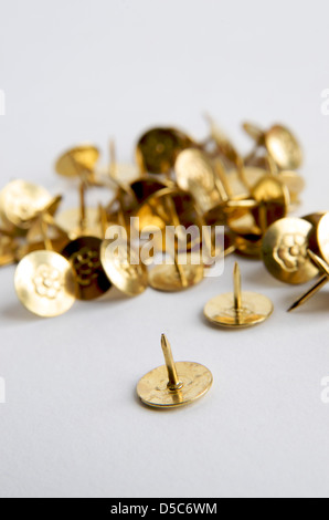 Sammlung von goldfarbenen Stecknadeln auf einer weißen Oberfläche für Büro- oder Bastelzwecke Stockfoto