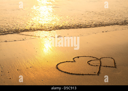 Herzen auf dem Sand des Strandes, weiche Welle des Meeres gezogen. Stockfoto