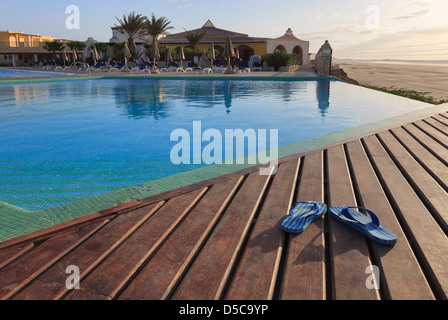 Paar Flip-flops auf Sonne decking leer Infinity-Pool in Luxus Ferienhotel auf Insel Boa Vista, Kapverden Stockfoto