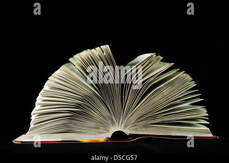 Aufgeschlagene Bibel auf schwarzem Hintergrund Stockfoto