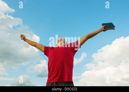 Junger Mann mit erhobenen Händen gegen blauen Himmel Stockfoto