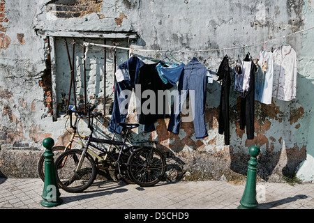 Waschen hängen zum Trocknen neben Fahrrädern in einer Straße in Macau Stockfoto