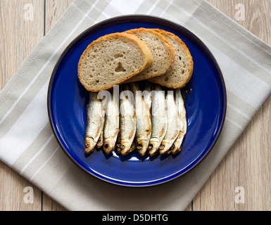 Geräucherte Sprotten mit Brot auf Küchentisch Stockfoto