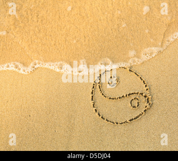 Yin Yang Symbol - geschrieben im Sand am Strand Textur - weiche Welle des Meeres Stockfoto