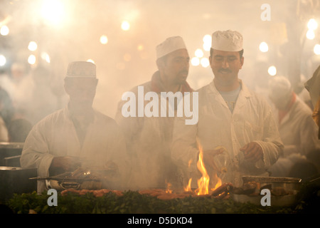 Männer kochen über einem rauchigen Feuer auf einem Wochenmarkt Stand in Djemaa al Fna Platz in Marrkesh, Marokko Stockfoto