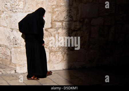 Jerusalem, Israel. 29. März 2013.  Eine alte Nonne geht von Licht in Schatten, wie sie den Eingang zur Kirche von der Grabeskirche am Karfreitag nähert. Jerusalem, Israel. 29. März 2013.  Von christlichen Pilgern gingen die letzten Schritte des Jesus durch die Via Dolorosa, die Kirche des Heiligen Grabes am Karfreitag, singen und singen in einer Mischung aus Sprachen, Trachten und Traditionen. Bildnachweis: Nir Alon / Alamy Live News Stockfoto