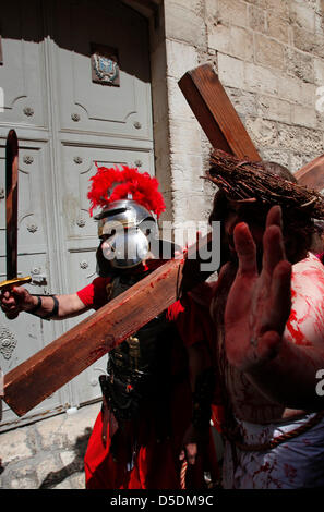 Ein Christ devotee gekleidet, wie Jesus Christus trägt ein hölzernes Kreuz reenacting die Stationen des Kreuzes während der Karfreitagsprozession entlang der Via Dolorosa Straße glaubte, daß der Weg zu sein, dass Jesus auf dem Weg zu seiner Kreuzigung in der Altstadt Ost Jerusalem, Israel ging Stockfoto