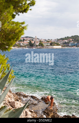 Ein weiblicher Schwimmer im Vordergrund abtrocknen nach dem Schwimmen an einem der Stein Strände von Hvar. Stockfoto