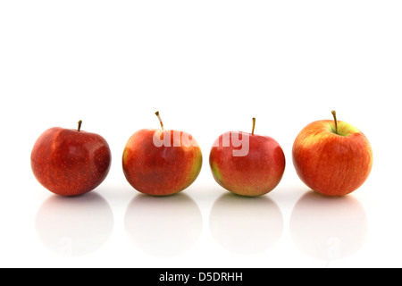 Vier rote Äpfel in einer Reihe, auf weißem Hintergrund reflektiert. Stockfoto